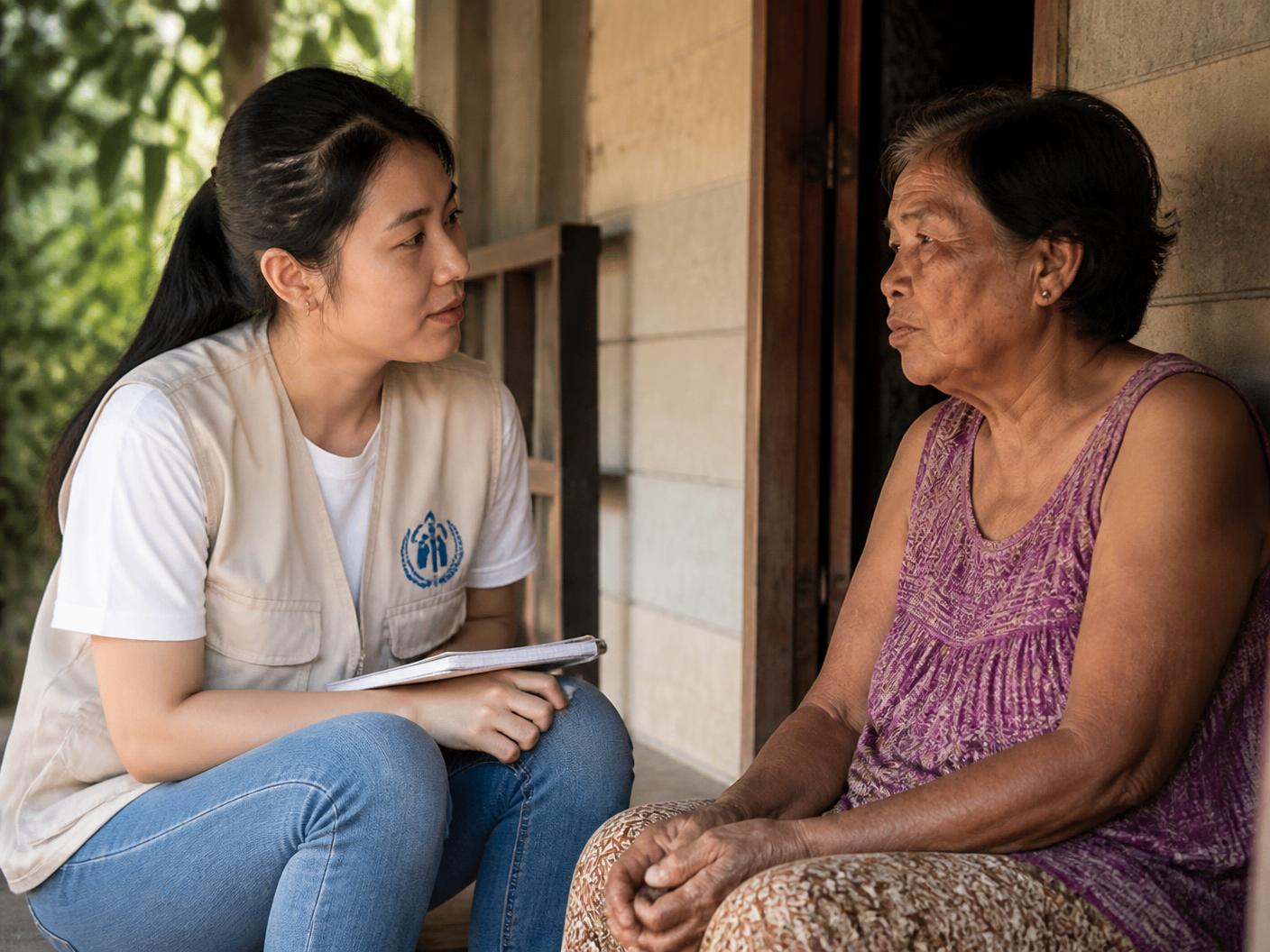 A community health worker seated beside a resident, listening during a screening day consultation